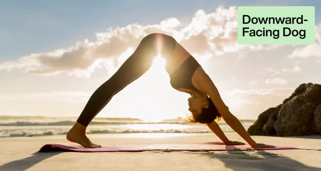 a women doing downward facing dog in open beach